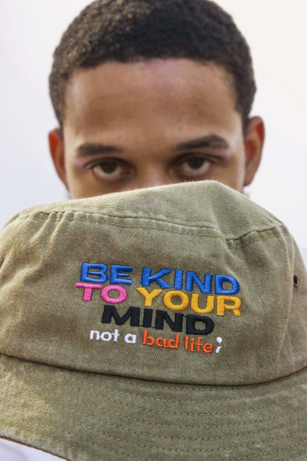 Man-holding-Be-Kind-to-Your-Mind-Bucket-Hat