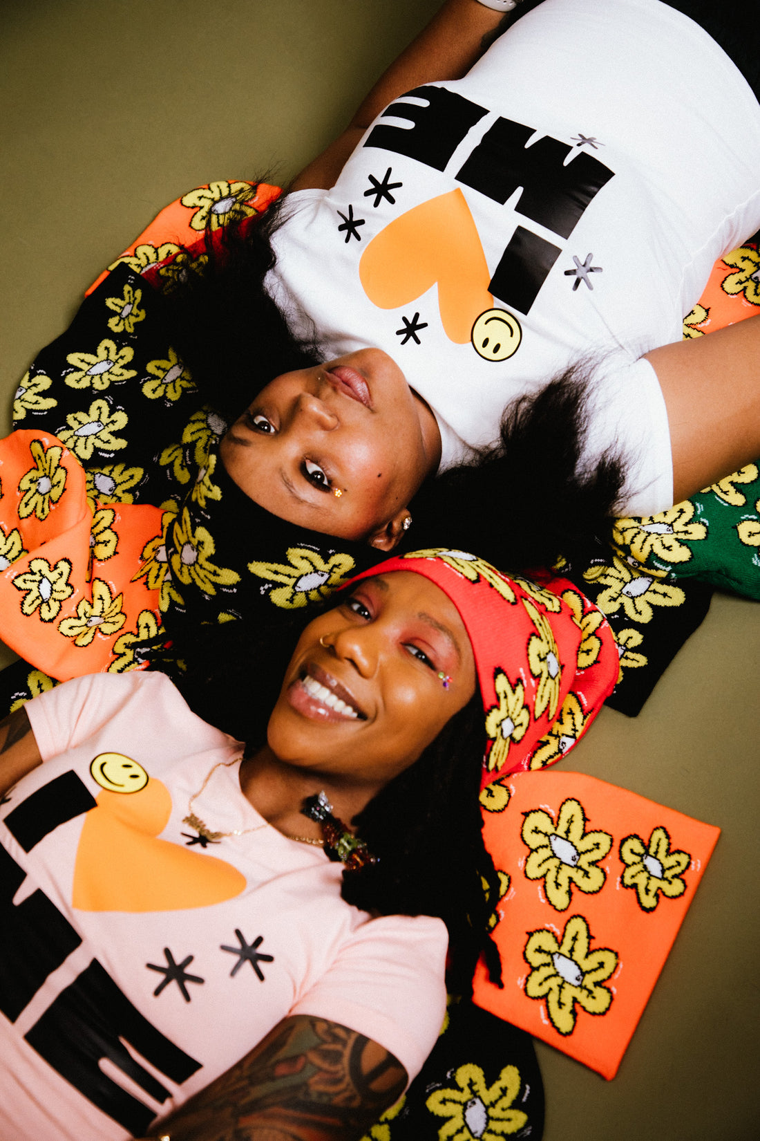 Two girls laying on a pile of Not A Bad Life's flower beanies